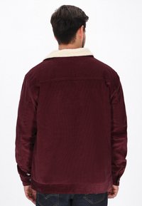 Burgunderfarvet cordurojjakke med en cremefarvet lammeskindskrave, med en lige pasform og knapmanchetter, designet til en afslappet pasform.