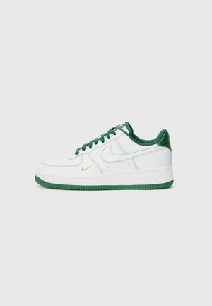Sneaker Nike Air Force 1 bianco con accenti verdi, dotato di una tomaia liscia, punta rotonda, fori per la traspirabilità e logo dorato.
