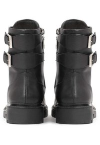 Black leather ankle boots featuring two adjustable straps with silver buckles, a rounded toe, and a chunky rubber sole.