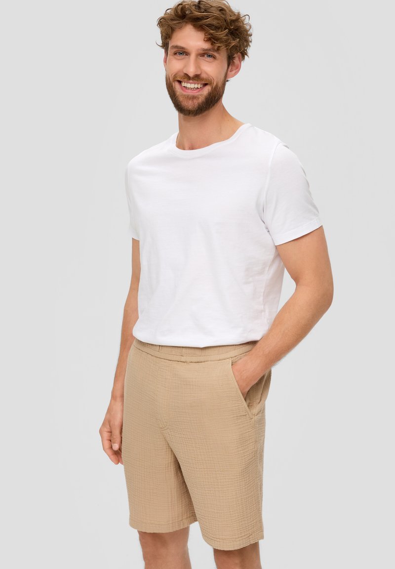 Biele tričko s krátkym rukávom v kombinácii s béžovými textúrovanými šortkami s vreckami, rovný strih a elastický pás. Jednoduchý, neformálny outfit.