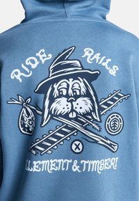 Felpa blu con cappuccio raffigurante un coniglio con un cappello, tronchi incrociati e una borsa. Il testo recita "RIDE RAILS ELEMENT & TIMBER!" in bianco.