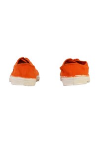 Une paire de chaussures en toile orange à enfiler avec des semelles en caoutchouc blanches, vues de l'arrière sur un fond blanc.