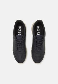 Marine lærersneakers med perforerte detaljer, flate lisser og en kontrastfarge beige såle. Har "BOSS"-merke på innersålen.