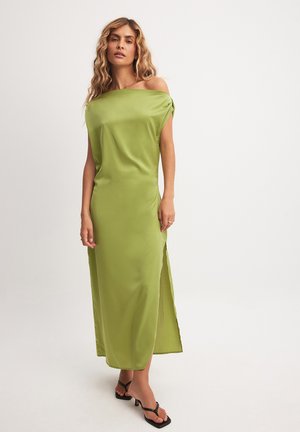 Vestido largo de satén verde brillante, con escote off-shoulder. Presenta una abertura lateral y una textura suave y lisa. Mangas abiertas para un ajuste relajado.