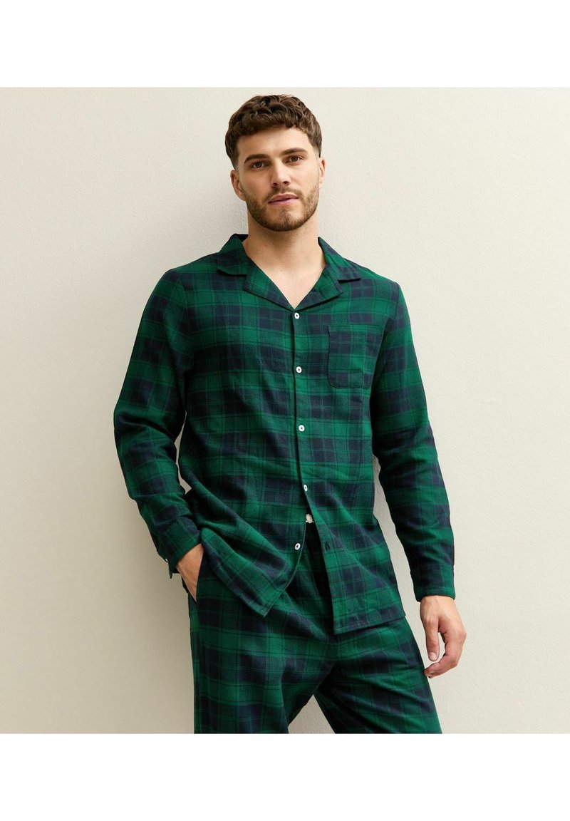 Completo pigiama a quadri verdi in flanella, con camicia abbottonata e taschino sul petto, e pantaloni abbinati in vestibilità comoda.