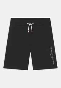 Černé šortky s pružným pasem a šňůrkou, zdobené červenými a bílými akcenty. Na levé nohavici je vytištěno "TOMMY HILFIGER EST. 1985" bílým textem.