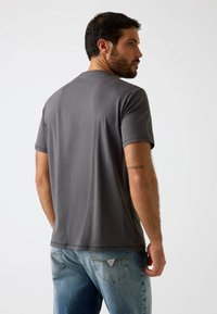 Graues Baumwoll-T-Shirt mit kurzen Ärmeln, rundem Ausschnitt und glatter Textur, kombiniert mit hellblauen Jeans aus Denim mit dezenten Steppnähten.