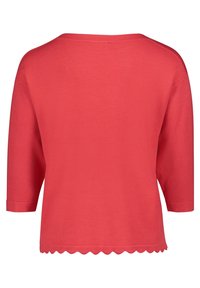 Korallefarbenes Strickoberteil mit lockerer Passform, 3/4-Ärmeln und gewelltem Saum. Glatte Textur ohne Muster oder Verzierungen.