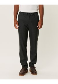 Pantalons légers gris foncé avec une taille élastique et un cordon de serrage. Le design présente une coupe fuselée et une texture lisse.