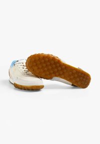 Sneaker blanche avec des accents bleu clair et une semelle en caoutchouc. Présente un cuir lisse et du daim, un bout rond, et une bande de traction sur la semelle extérieure.