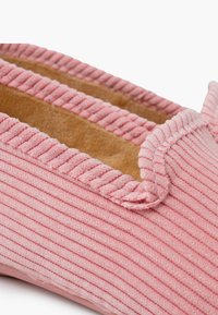 Chausson en velours côtelé rose avec texture striée, bout rond et doublure contrastante beige. Avec des détails de bordure cousus.