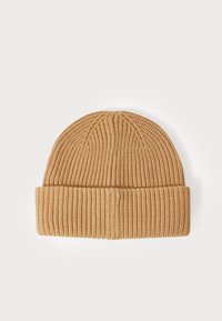 Knit beanie in light brown. Features ribbed texture and a folded cuff. Rounded top with vertical knit pattern. Soft material.