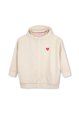 Sweat à capuche couleur crème avec fermeture éclair devant et logo cœur rouge sur la poitrine gauche portant l'inscription "HUGO" en lettres blanches.