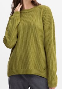 Sweter dzianinowy w oliwkowej zieleni z teksturowanym wzorem, okrągłym dekoltem i ściągaczami; posiada mały guzik dekoracyjny z boku.