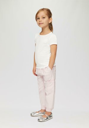 Witte t-shirt met korte mouwen en een tekstuur van bloemen, gecombineerd met lichtroze elastische broek en zilveren ballerina's met strikken.