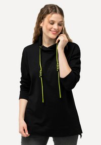 Sudadera negra con cuello tipo cowl, con cordones neón verdes y un discreto patrón decorativo. Tejido suave, corte holgado y mangas largas.
