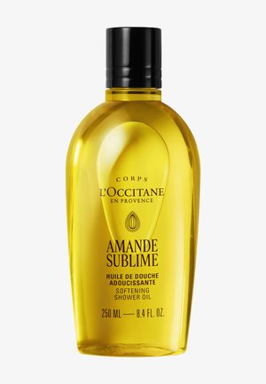 Bottiglia trasparente gialla di olio doccia ammorbidente L'Occitane Amande Sublime, 250 ml con tappo nero.