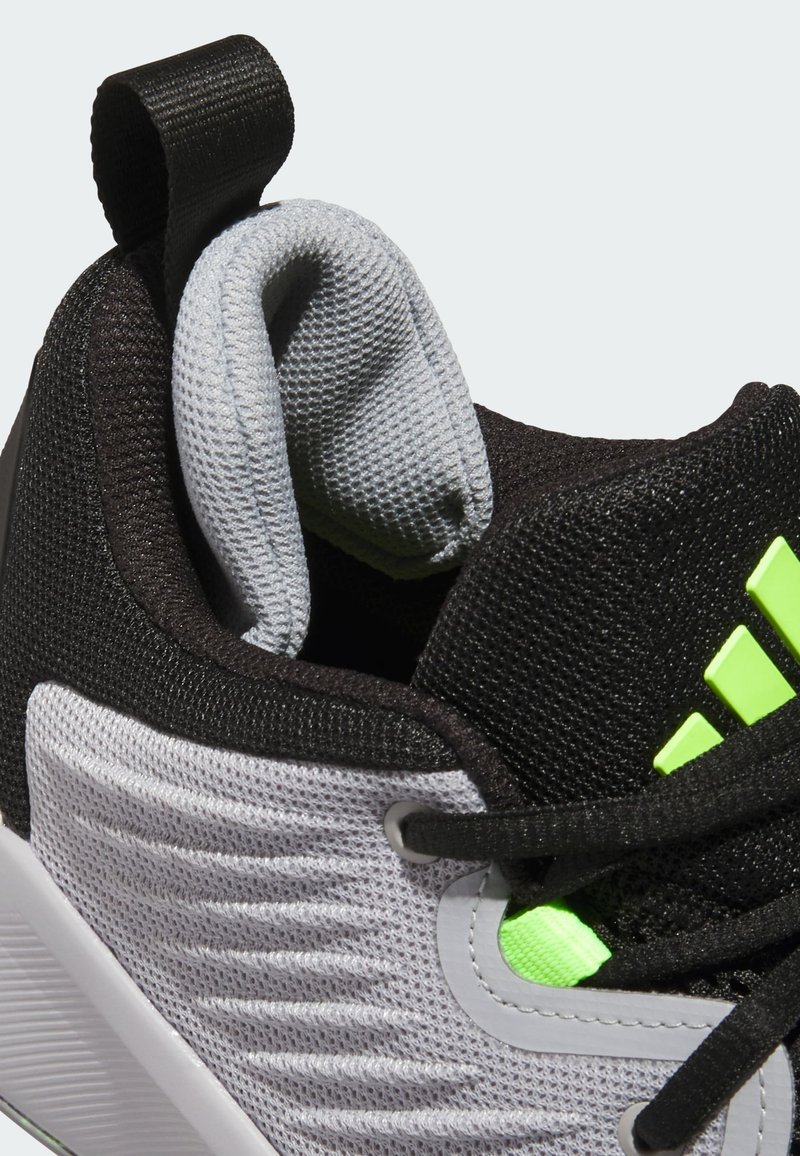 Sneakers noirs et gris avec un matériau en maille, des accents texturés, des détails verts et une languette à l'arrière pour un enfilage facile.