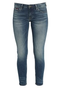 Jeans ajustados de denim, color azul claro con desgastado, sutil decoloración, diseño de cinco bolsillos y cierre de botón metálico.