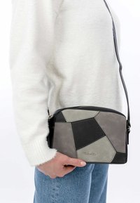 Borsa a tracolla geometrica grigio e nera con una tracolla, realizzata in suede testurizzato e pelle, con chiusura a zip.
