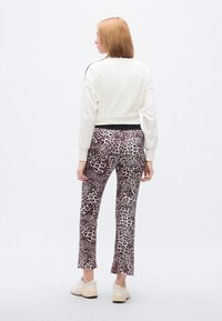 Λευκό κοντό φούτερ με μαύρες λεπτομέρειες, συνδυασμένο με εφαρμοστά παντελόνια με μοτίβο λεοπάρδαλης σε μωβ και μαύρο. Απαλά παπούτσια.