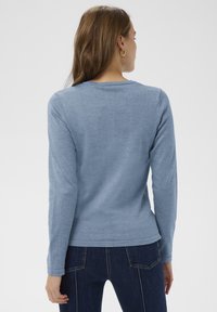 Gaiši zils garo piedurknu džemperis ar apaļu kakla izgriezumu, izgatavots no mīksta auduma, ar gludu virsmu un smalkām šuvju detaļām.