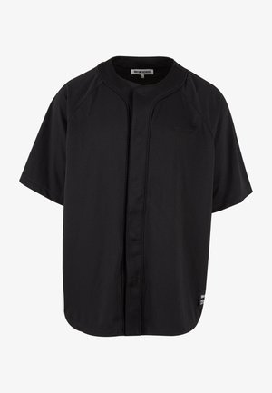 Fekete, rövid ujjú mez, lélegző hálós anyagból készült. Elöl gombos záródású, raglán ujjak jellemzik, és egy kis logó található a mellen.