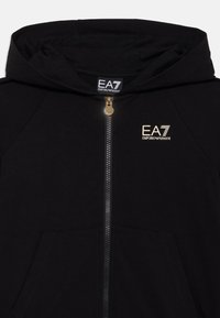 Schwarze Reißverschluss-Hoodie aus Baumwollmischung, mit Kapuze, Fronttaschen und einem goldenen EA7-Logo auf der Brust. Glatte Textur und atmungsaktives Design.