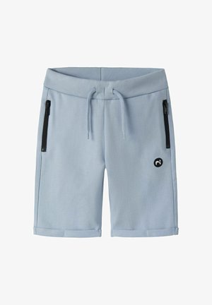 Shorts décontractés bleu clair avec taille côtelée, cordon de serrage, poches latérales zippées noires, ourlets retroussés et petit logo noir sur la jambe gauche.