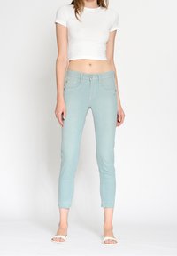 Jasnoniebieskie, obcisłe jeansy z wysokim stanem, podkreślającymi przednie kieszenie i postrzępionym dołem. Połączone z białym, krótko przyciętym t-shirtem i sandałami.