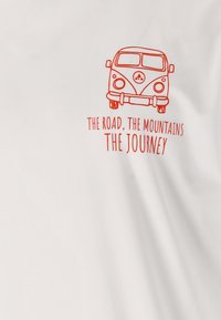 Vit t-shirt med en orange grafisk bild av en vintage skåpbil, med texten: "Vägen, bergen, resan." Enkelt mönster, mjuk textur.