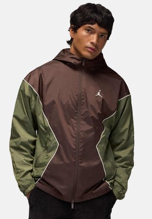 Lichtgewicht jas in bruin en groen met een capuchon, elastische manchetten en een ritssluiting aan de voorkant. Voorzien van witte accenten en een logo op de borst.