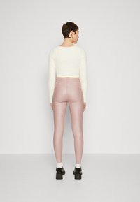 Rosa faux skinnbukser med slim fit, parret med en hvid tekstureret cropped sweater og sorte platform sko.