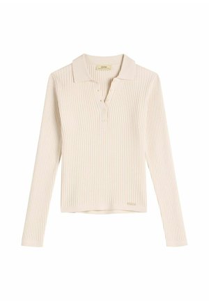 Kremowy prążkowany polo z długim rękawem, z rozcięciem na guziki i małą metką marki blisko brzegu.