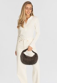 Borsa intrecciata marrone con una forma curvata e una superficie testurizzata. Presenta un manico singolo e una struttura morbida e flessibile.