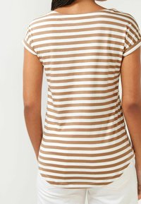 Brun og hvid stribet T-shirt med korte oprullede ærmer, rund bund og blødt bomuldsstof. Bagsiden har en diskret sømdetalje.