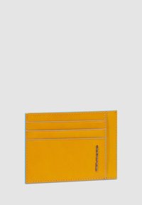 Geel leren kaarthouder met vier sleuven en een zilveren logoaccent. Kenmerkt zich door een gladde textuur en contrasterende lichtblauwe rand.