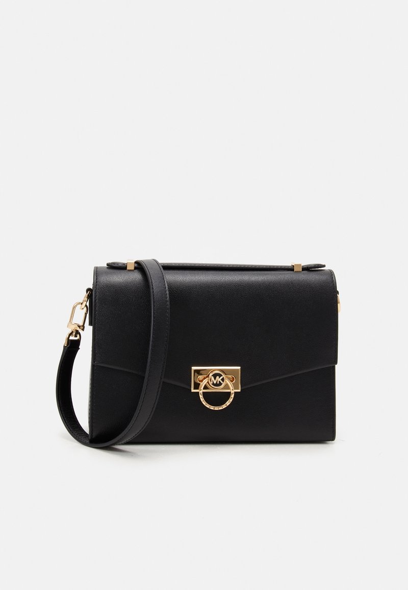 Bolso de mano de cuero negro con forma rectangular, herrajes dorados y un acento circular. Presenta una correa desmontable y una textura suave.