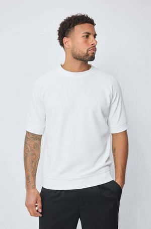 Sweatshirt blanc à manches courtes avec un design texturé, col et poignets côtelés. Tissu doux avec une coupe décontractée et une ligne d'ourlet.