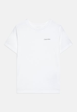 Balta medvilninė marškinėliai su trumpomis rankovėmis ir apvaliu kaklu. Ant kairiojo krūtinės yra mažas pilkas "Calvin Klein" logotipas.