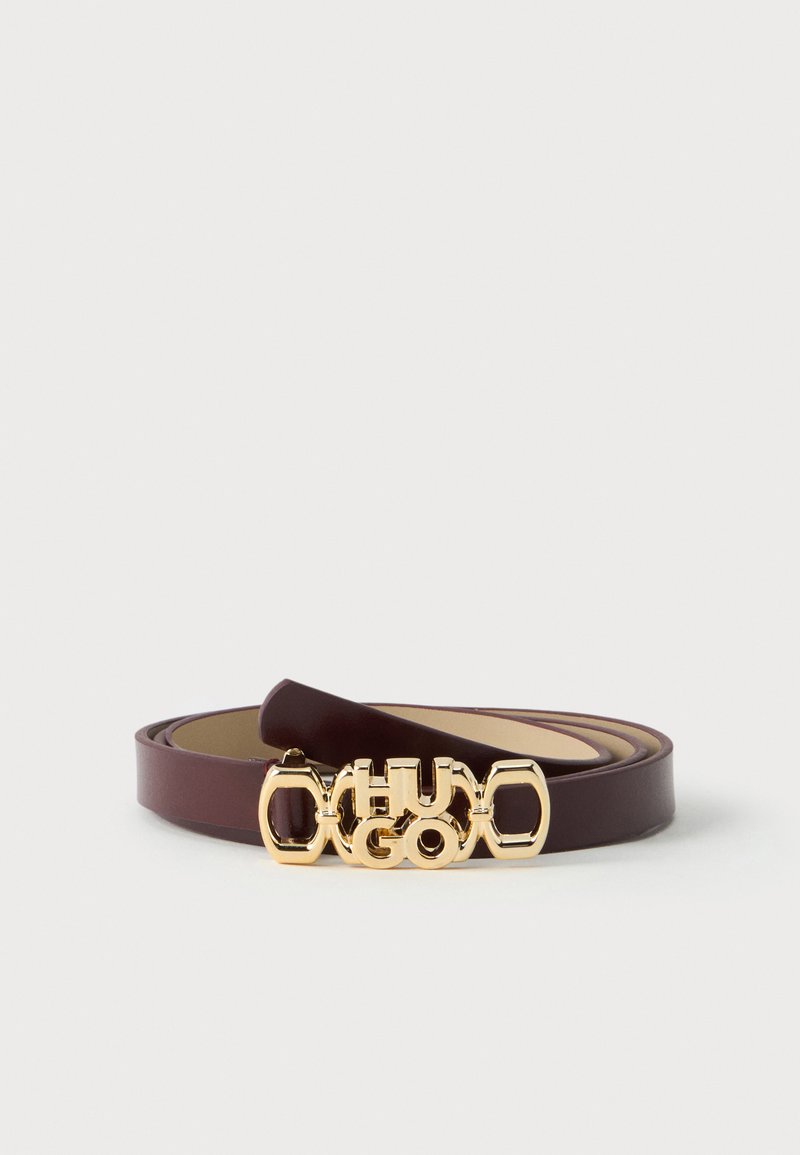 Ceinture en cuir marron avec boucle dorée présentant le logo du créateur en relief, posée à plat sur un fond clair.