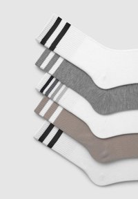 Calzini in cotone misto impilati in tonalità di bianco, grigio e beige, con texture a costine e strisce in contrasto sui polsini.