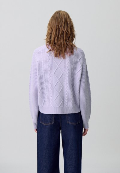Maglione lilla lavorato a maglia con design a treccia e motivi a diamante, con taglio cropped e orlo a coste. Abbinato a jeans scuri.