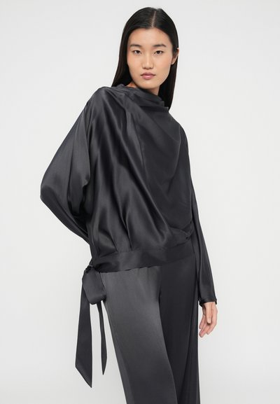 Top din satin gri închis cu design drapat, mâneci lungi și un accent legat în talie, asortat cu pantaloni din satin.