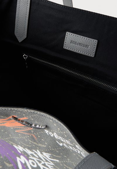 Μαύρη τσάντα tote εσωτερικά με φερμουάρ, γκρι δερμάτινες λαβές και γκρι ετικέτα με την ένδειξη "ZADIG & VOLTAIRE."