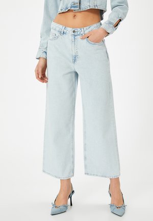 Jeans de tiro alto en denim de color azul claro y pierna ancha, con cinco bolsillos y un ligero desgastado. Combinados con tacones de punta a juego.