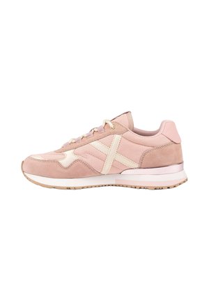Zapatilla deportiva de color rosa claro con detalles beige, cordones y suela blanca, mostrada desde el lado exterior sobre un fondo blanco.