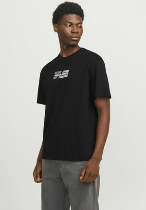 Camiseta de algodón negra con mangas cortas, que presenta un logotipo gráfico blanco en el pecho. Diseño simple con cuello redondo.