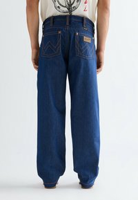 Σκούρο μπλε τζιν με φαρδιά εφαρμογή, διαθέτει χαρακτηριστική ετικέτα στην πίσω τσέπη και αντίθετη ραφή σε σχέδιο ζιγκ ζαγκ.