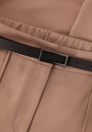 Pantalones de tela marrón claro con pliegues, que presentan un cinturón de cuero marrón oscuro con una hebilla metálica rectangular.